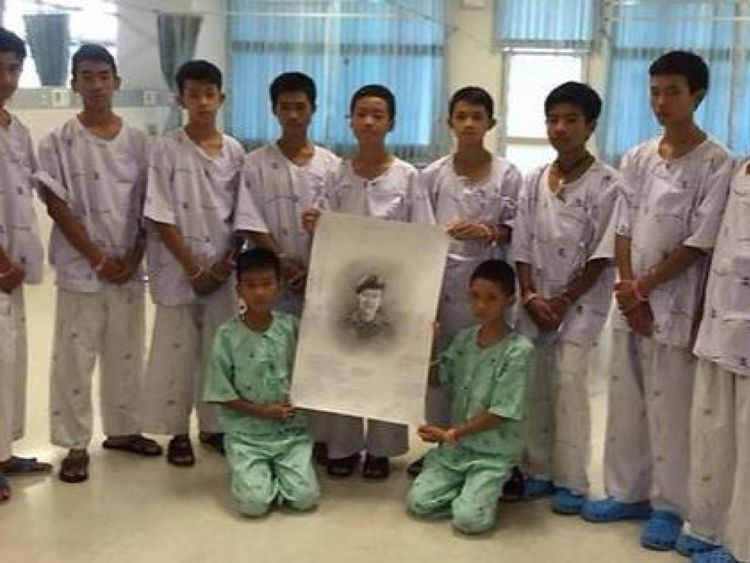 The boys with a picture of Saman Kunan who died during rescue mission
