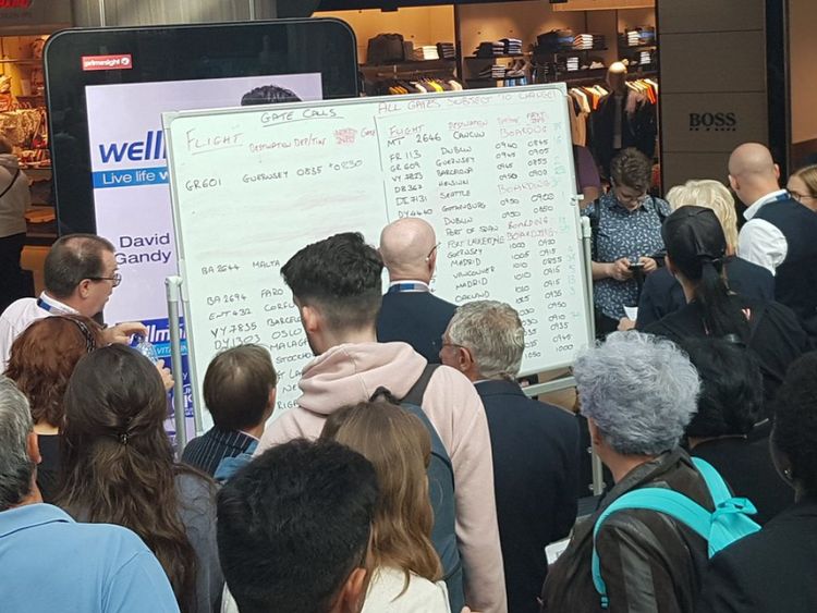 Passengers gather around a whiteboard with the information