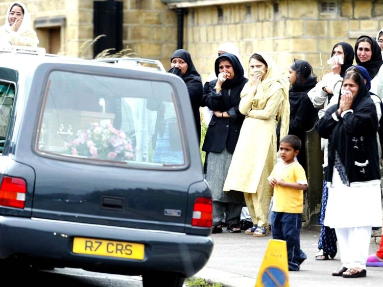 Mourners watch hearses carrying the Chishti family